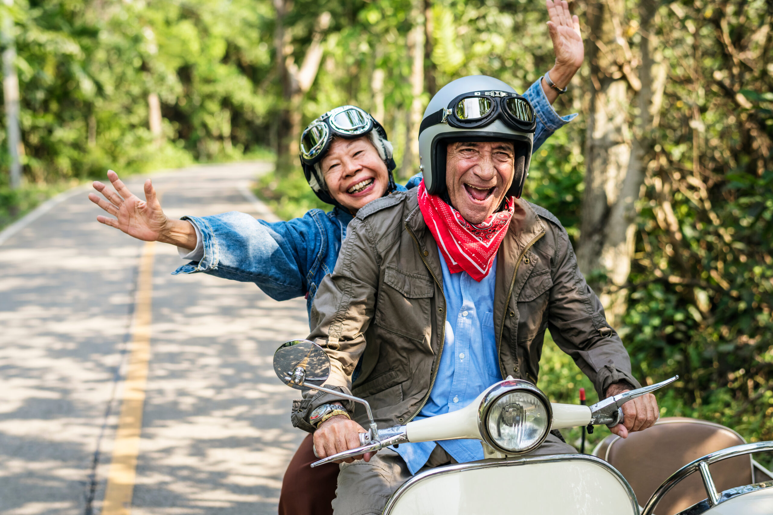 Senior couple gleefully riding on a moped together.